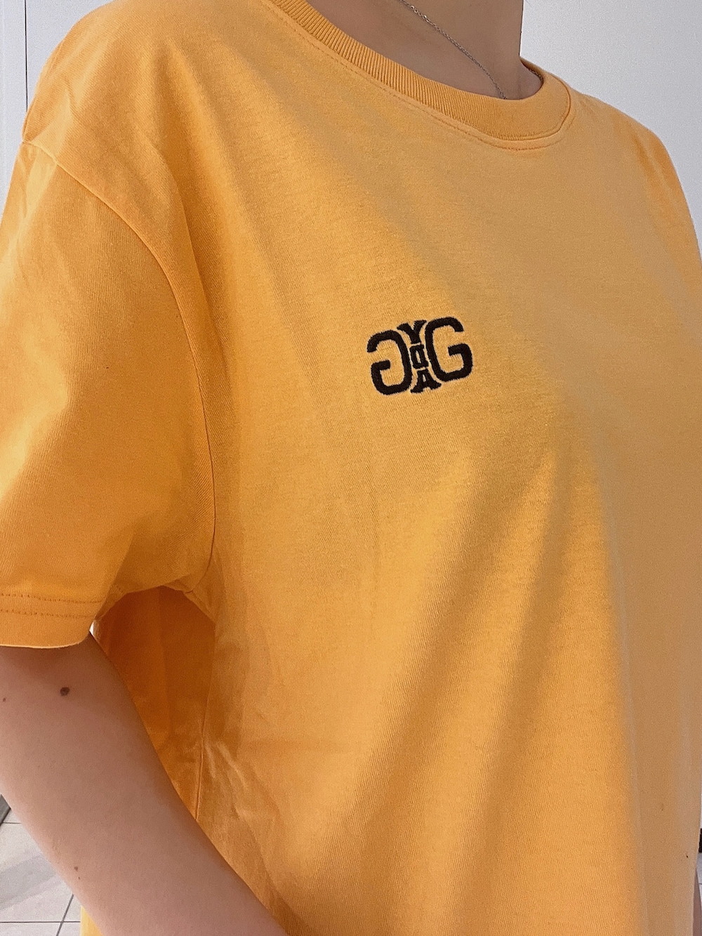 オレンジ系のTシャツ/カットソー、ブルー系のデニムパンツを着用したレディースの春コーディネートの7枚目の写真