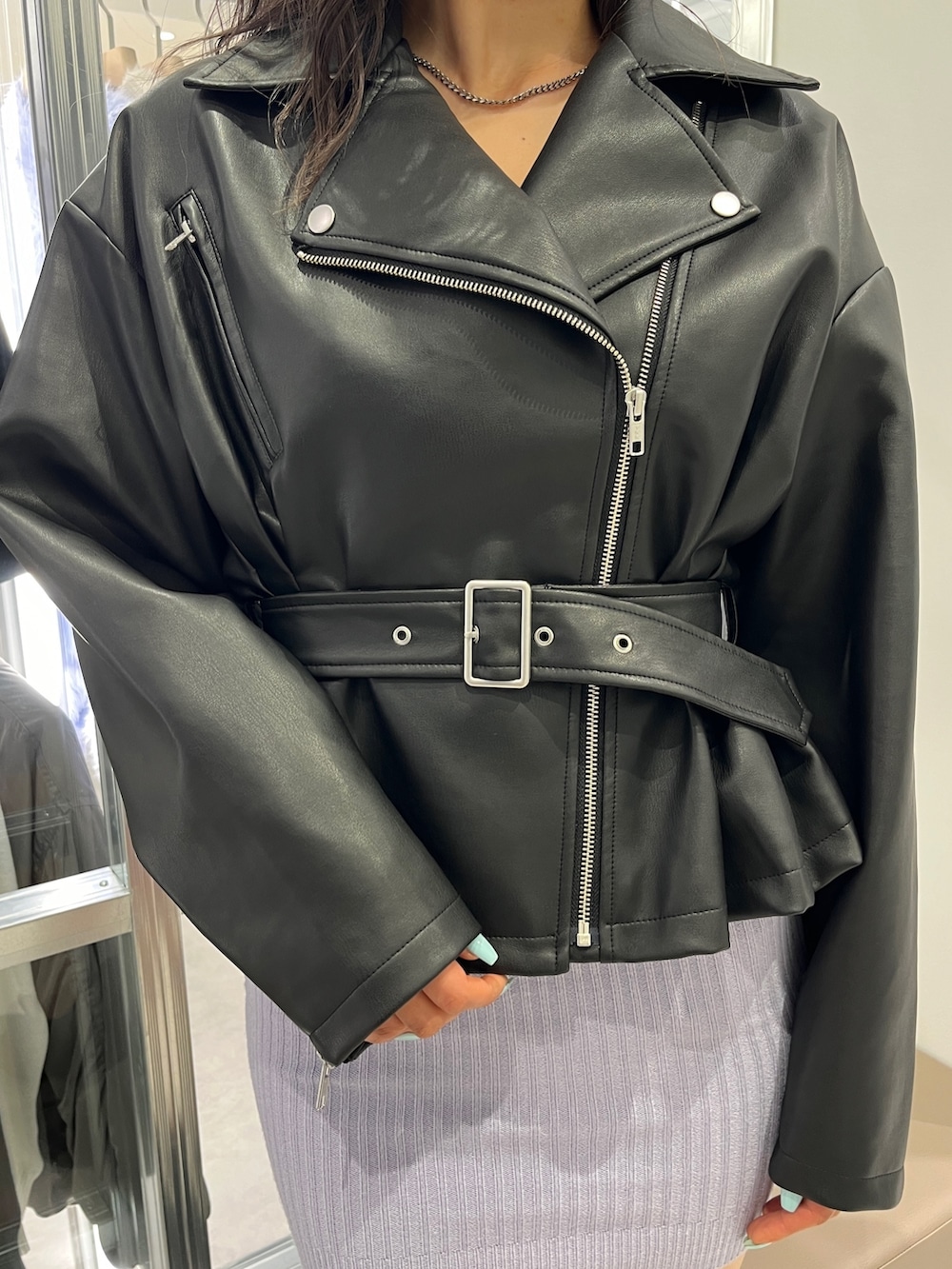 ブラック系のライダースジャケット、パープル系のワンピース、ブラック系のハンドバッグを着用したレディースの冬コーディネートの4枚目の写真