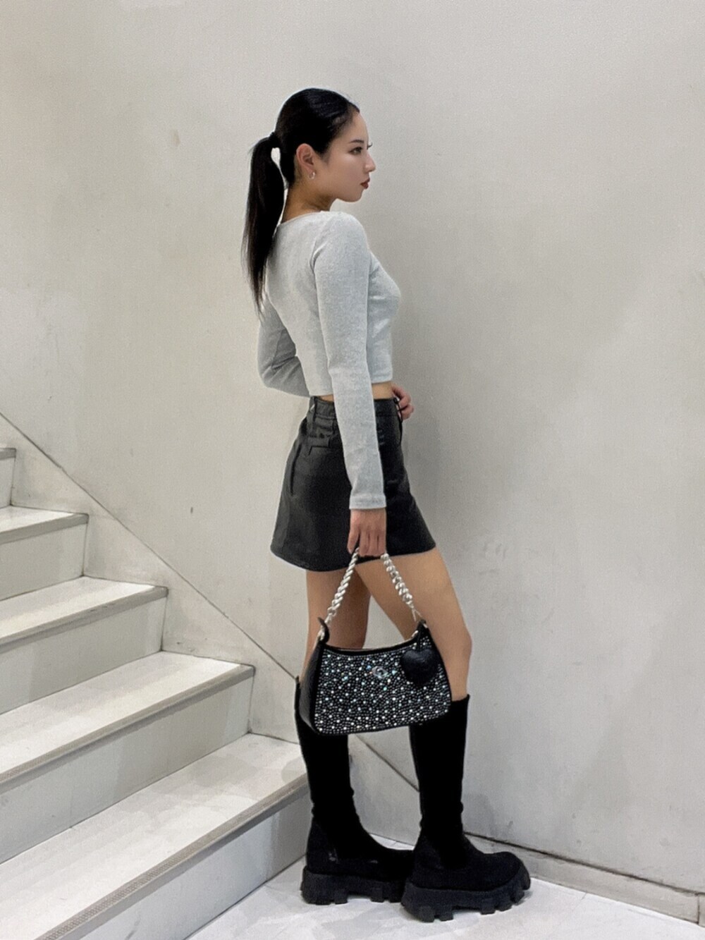 ブラック系のブーツ、ブラック系のスカート、グレー系のTシャツ/カットソーを着用したレディースの秋コーディネートの2枚目の写真