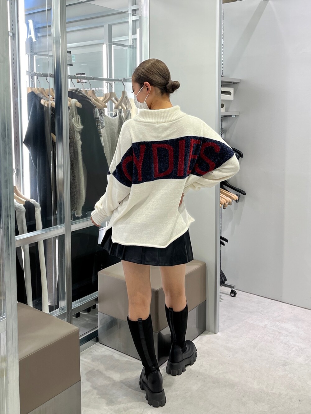 ホワイト系のニット/セーター、ブラック系のスカート、ブラック系のブーツを着用したレディースの秋コーディネートの2枚目の写真