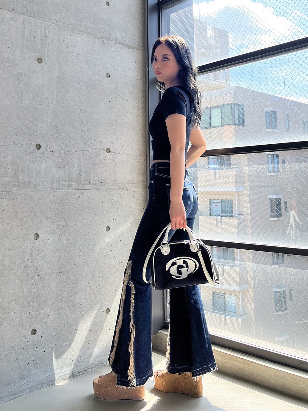 ブラック系のTシャツ/カットソー、ブルー系のデニムパンツ、ブラック系のハンドバッグを着用したレディースの春コーディネートの2枚目の写真