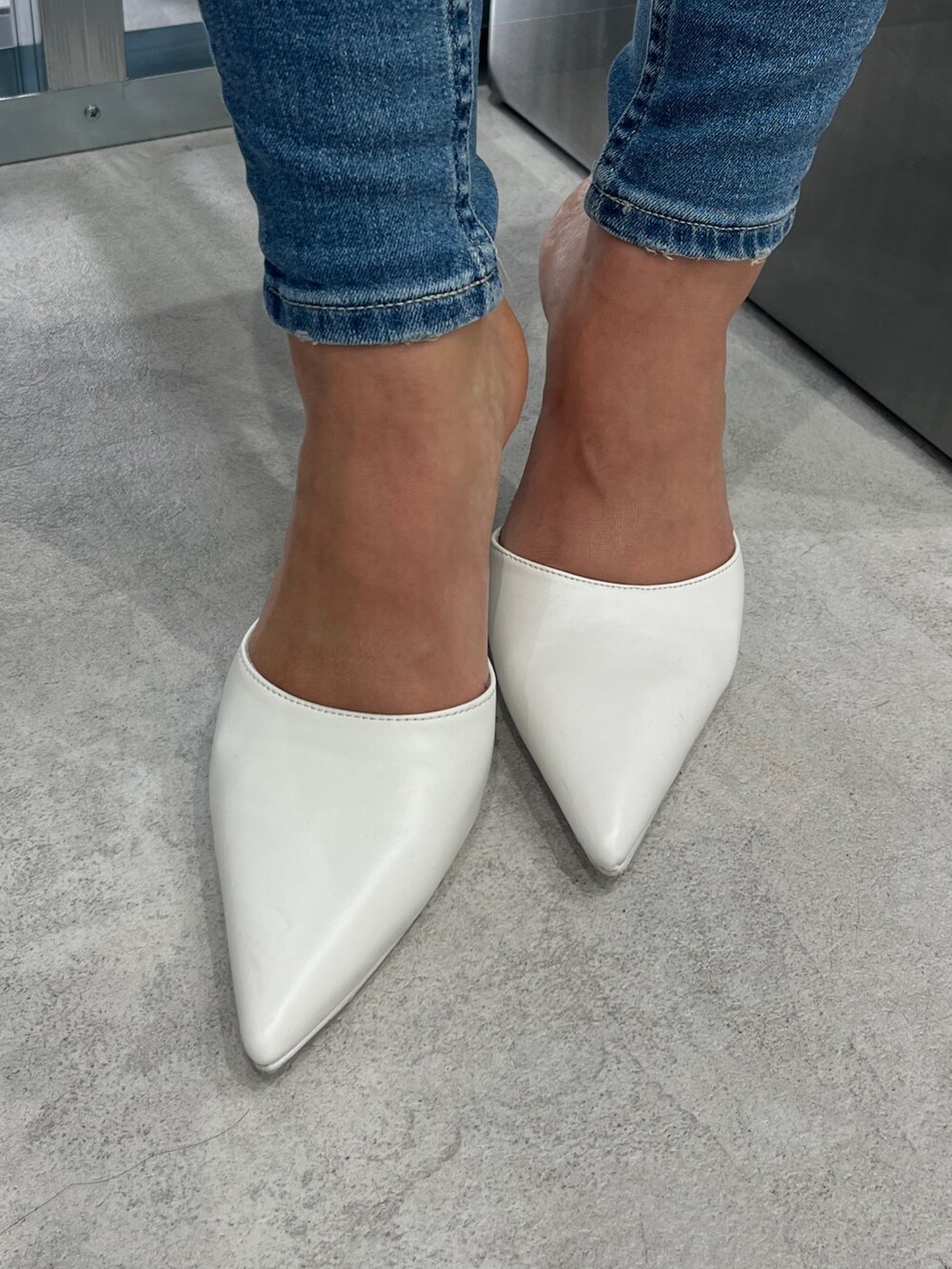 ホワイト系のパーカー、ブルー系のデニムパンツ、ホワイト系のパンプスを着用したレディースの冬コーディネートの6枚目の写真