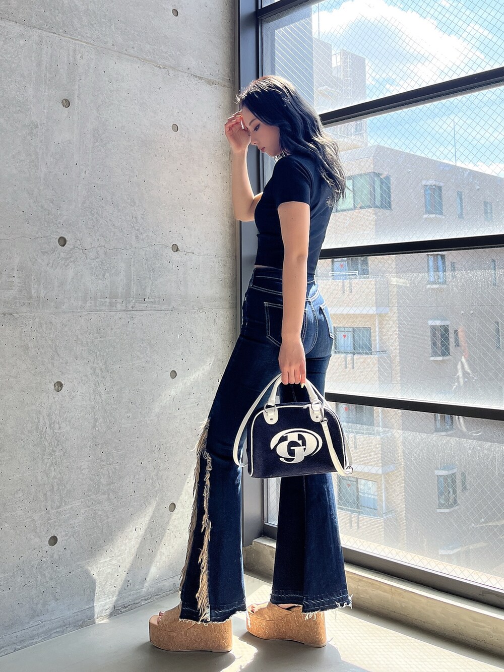 ブラック系のTシャツ/カットソー、ブルー系のデニムパンツ、ブラック系のハンドバッグを着用したレディースの春コーディネートの3枚目の写真