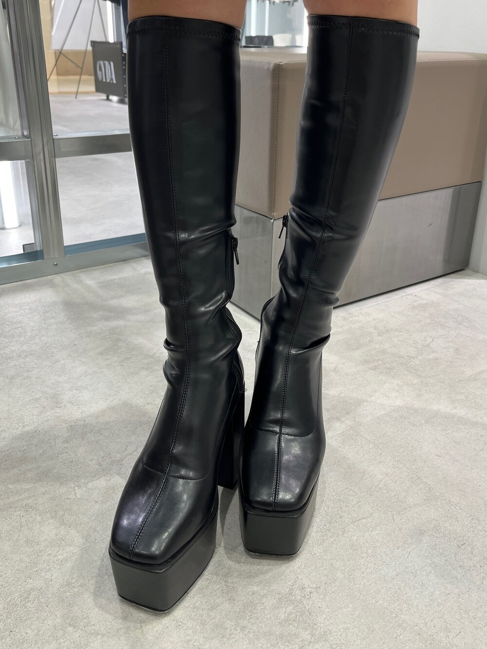 ブルー系のパーカー、シルバー系のハンドバッグ、ブラック系のブーツを着用したレディースの秋コーディネートの5枚目の写真