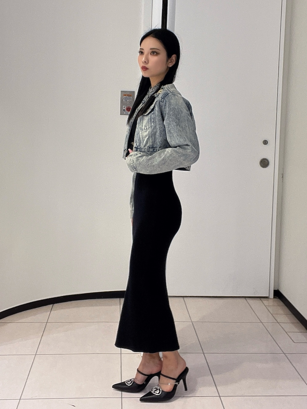 ブラック系のワンピース、ブラック系のパンプス、ブルー系のデニムジャケットを着用したレディースの春コーディネートの3枚目の写真