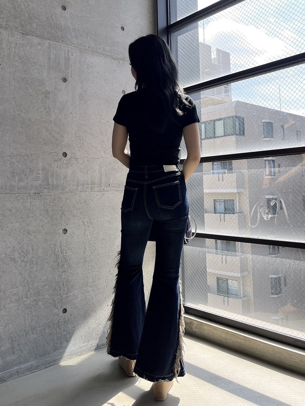 ブラック系のTシャツ/カットソー、ブルー系のデニムパンツ、ブラック系のハンドバッグを着用したレディースの春コーディネートの4枚目の写真