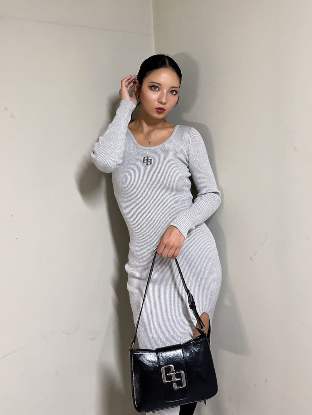 ブラック系のハンドバッグ、ブラック系のブーツ、シルバー系のワンピースを着用したレディースの秋コーディネートの4枚目の写真