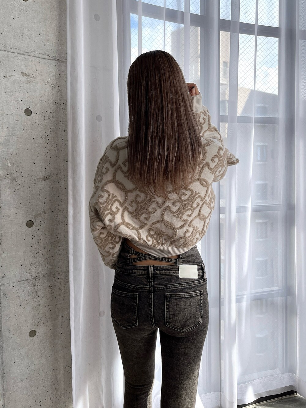 ホワイト系のニット/セーター、ブラック系のデニムパンツ、ホワイト系のブーツを着用したレディースの秋コーディネートの6枚目の写真