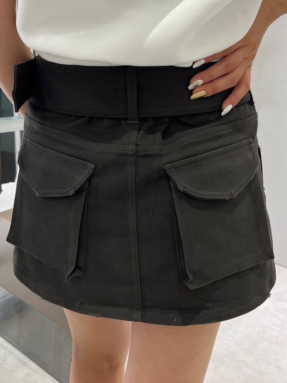 ホワイト系のパーカー、グレー系のスカート、ブラック系のブーツを着用したレディースの夏コーディネートの6枚目の写真