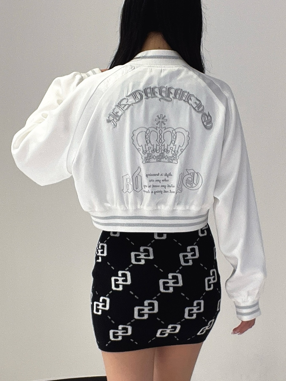 ブラック系のワンピース、ブラック系のブーツ、ホワイト系のブルゾンを着用したレディースの春コーディネートの6枚目の写真