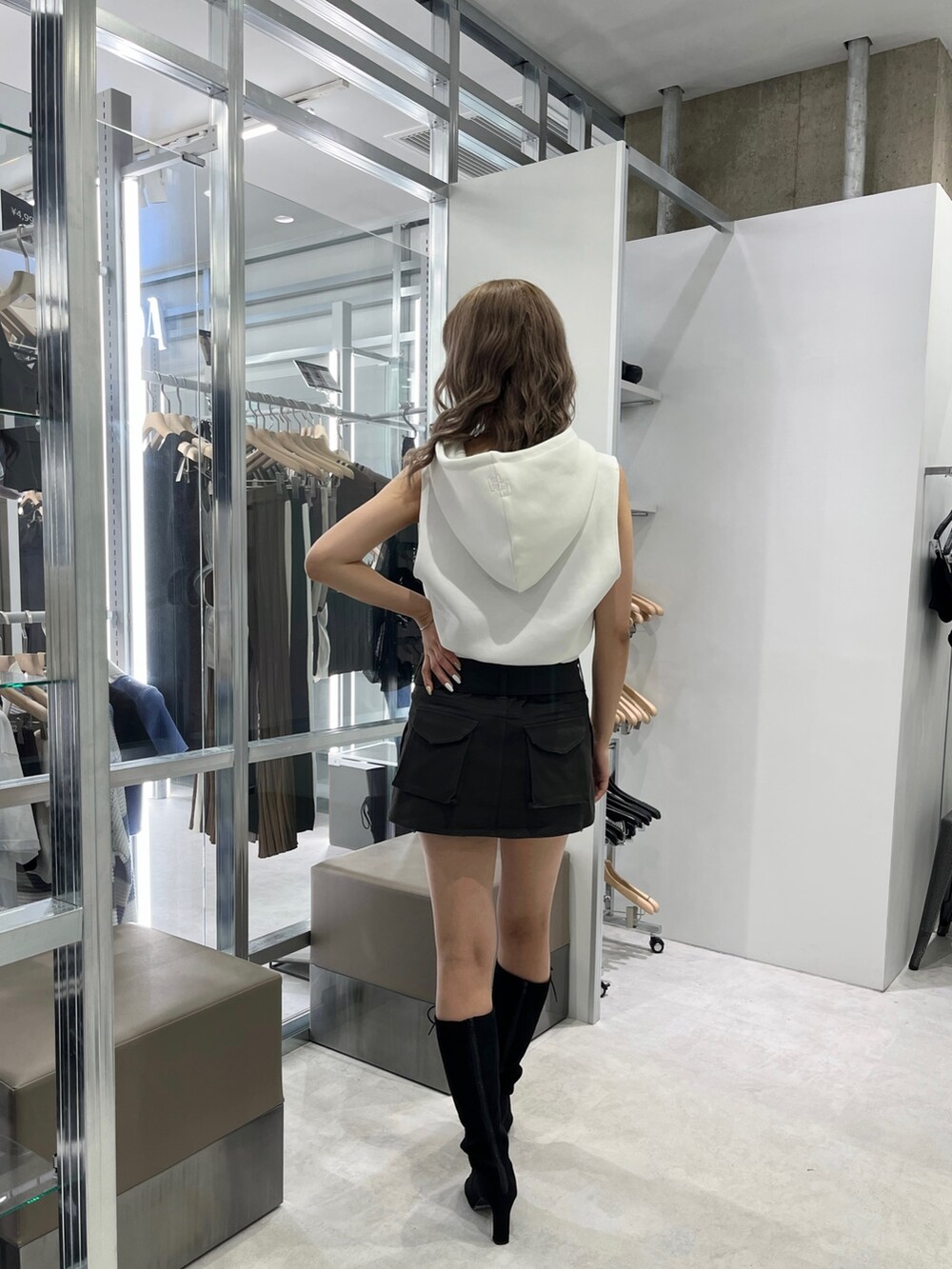 ホワイト系のパーカー、グレー系のスカート、ブラック系のブーツを着用したレディースの夏コーディネートの2枚目の写真