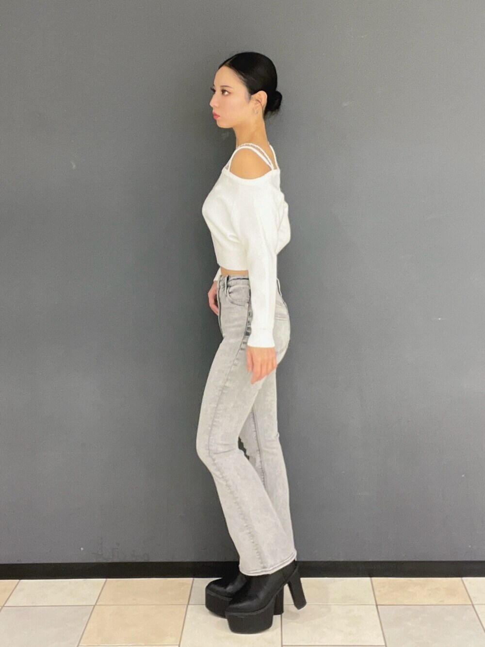 グレー系のデニムパンツ、ブラック系のブーツ、ホワイト系のニット/セーターを着用したレディースの秋コーディネートの3枚目の写真