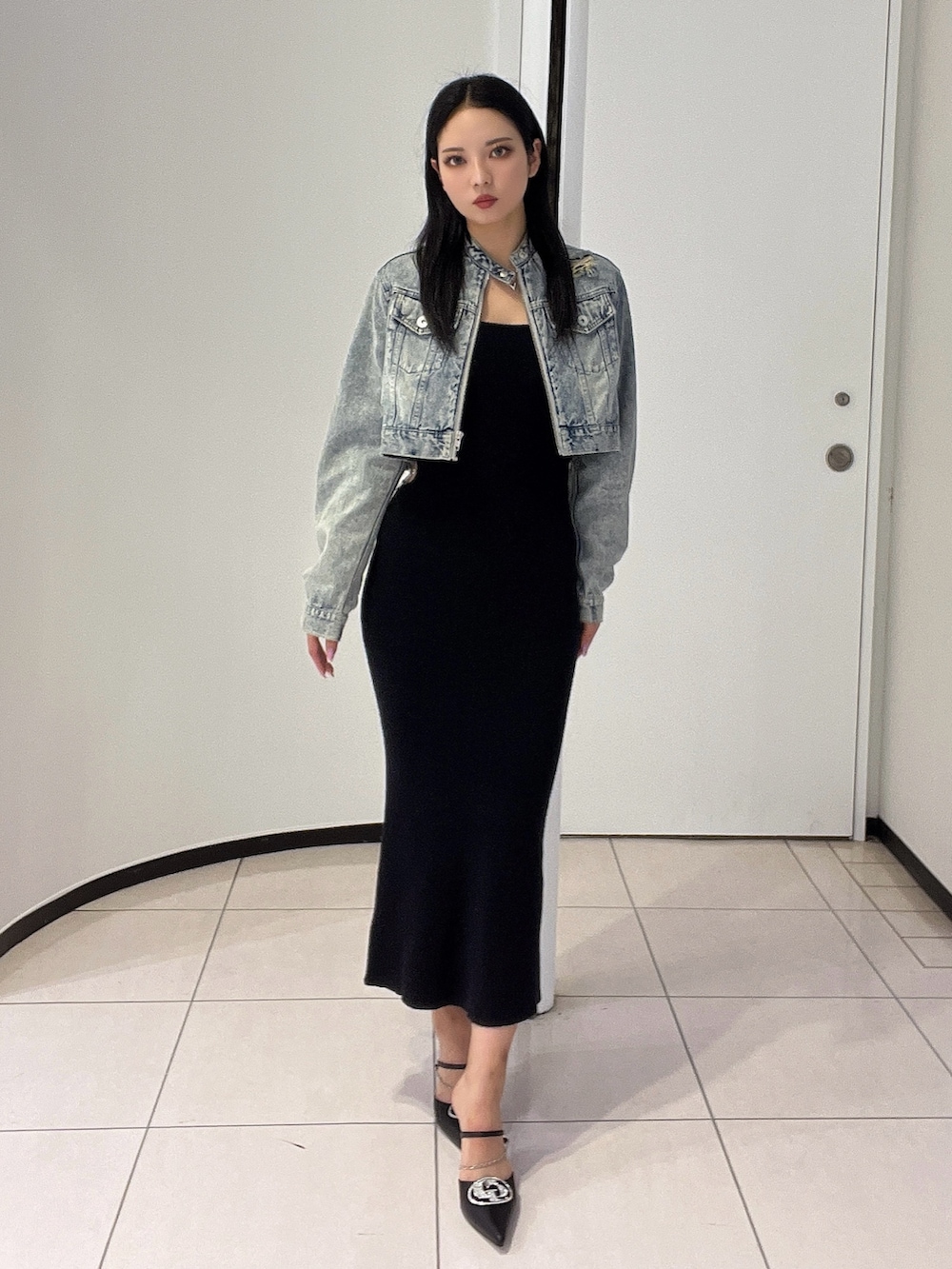 ブラック系のワンピース、ブラック系のパンプス、ブルー系のデニムジャケットを着用したレディースの春コーディネートの2枚目の写真