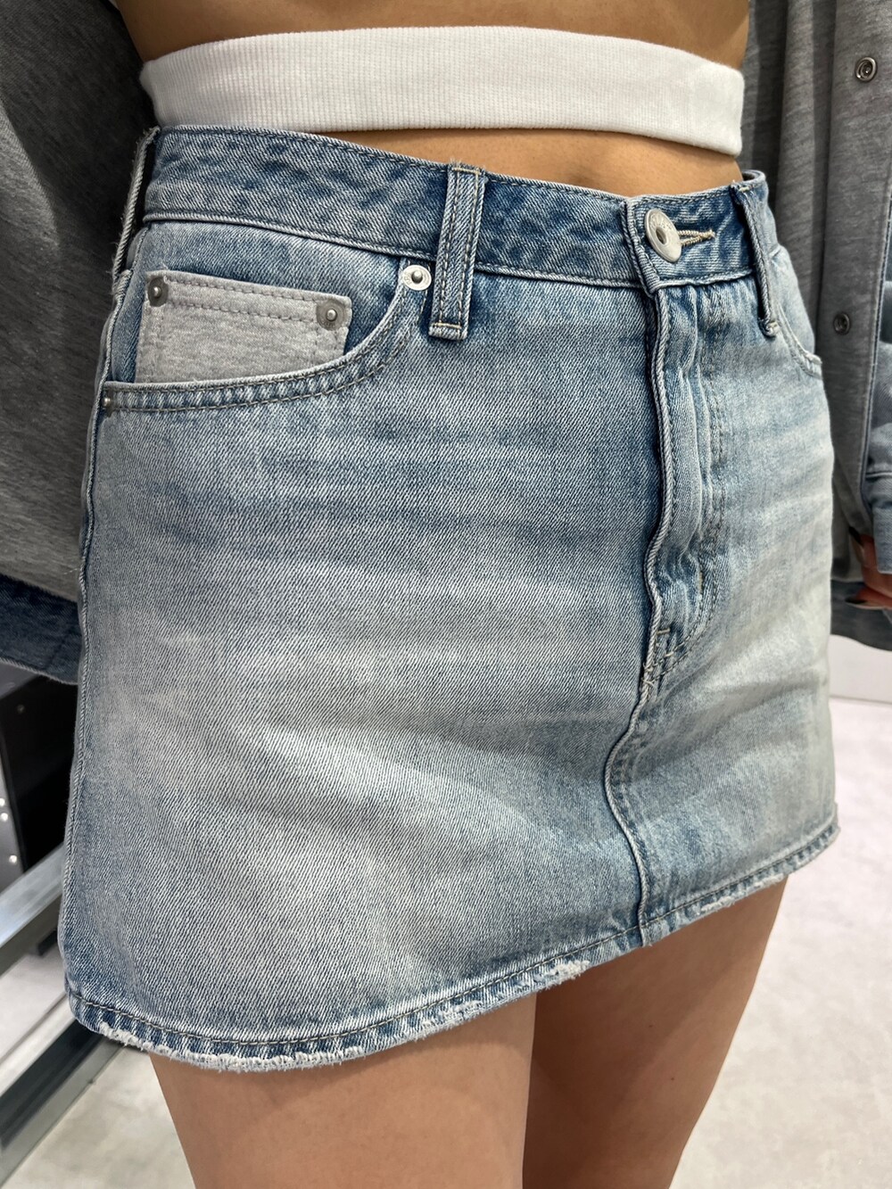 ホワイト系のタンクトップ、ブルー系のデニムジャケット、ブルー系のデニムスカートを着用したレディースの冬コーディネートの5枚目の写真