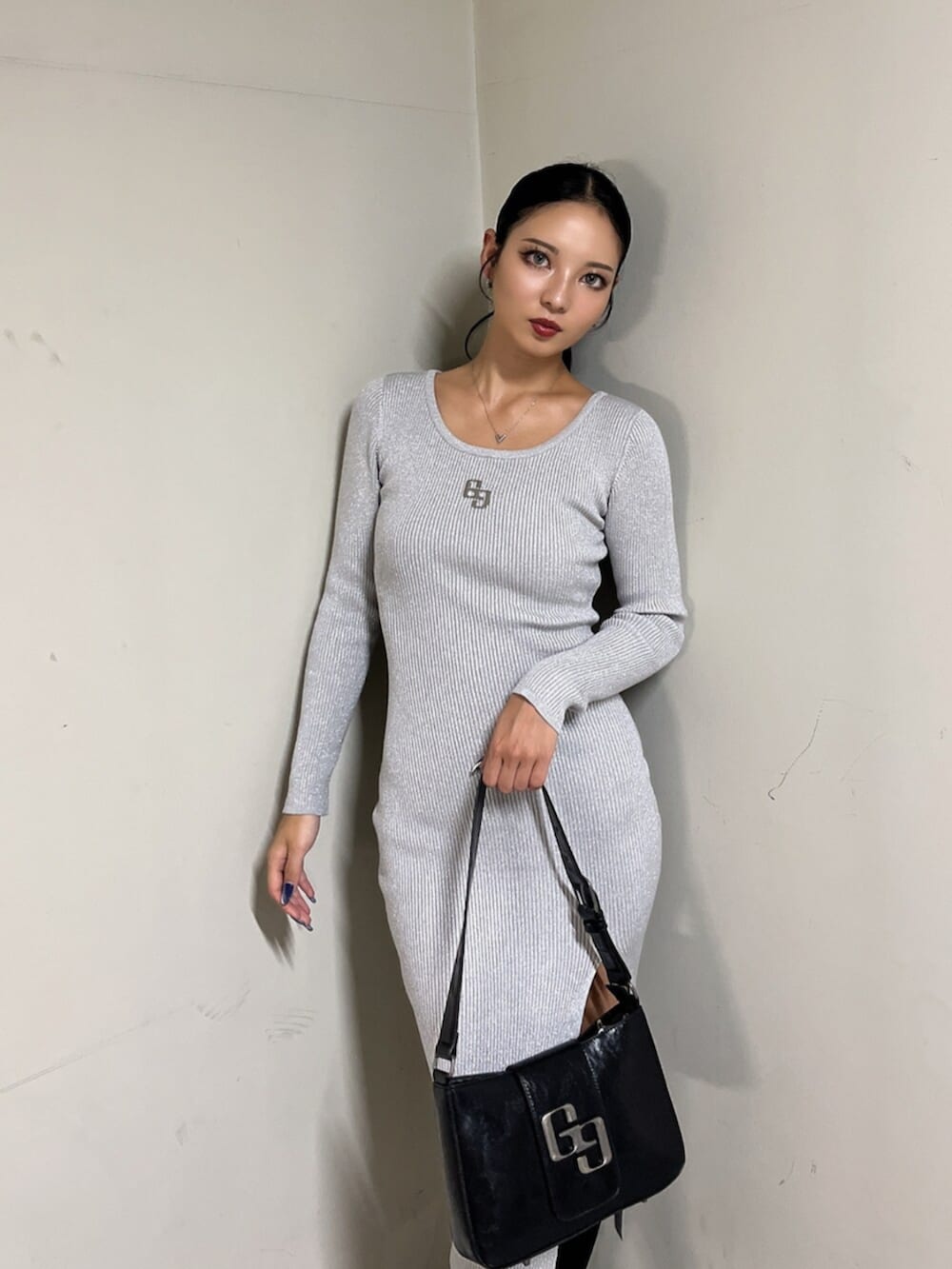 ブラック系のハンドバッグ、ブラック系のブーツ、シルバー系のワンピースを着用したレディースの秋コーディネートの6枚目の写真