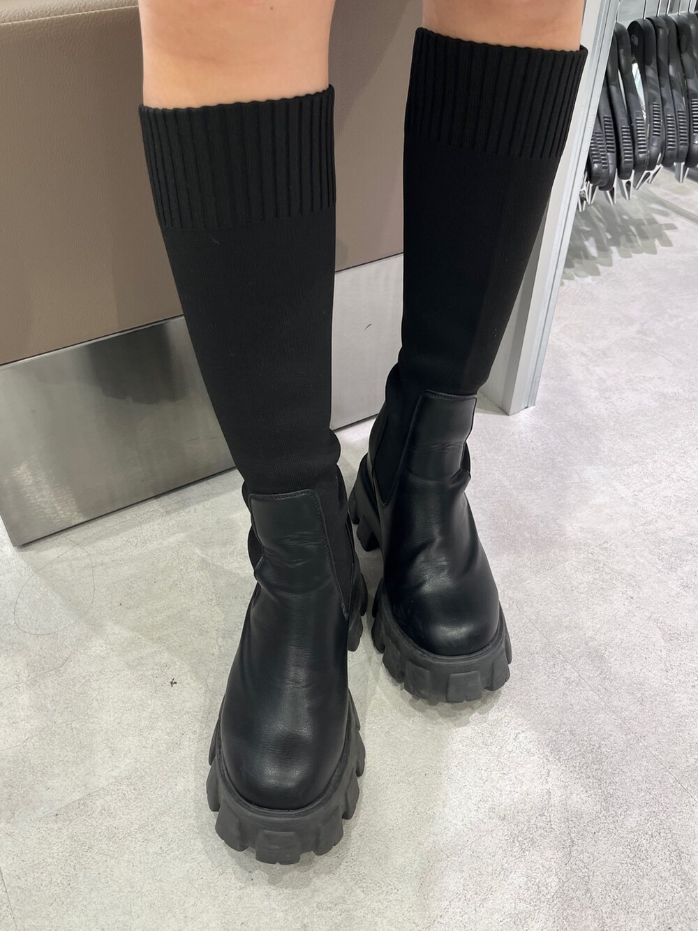 ホワイト系のニット/セーター、ブラック系のスカート、ブラック系のブーツを着用したレディースの秋コーディネートの5枚目の写真