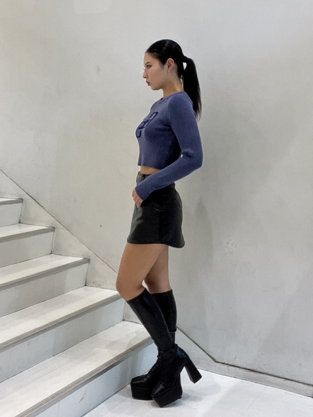 ブルー系のニット/セーター、ブラック系のスカート、ブラック系のブーツを着用したレディースの秋コーディネートの3枚目の写真