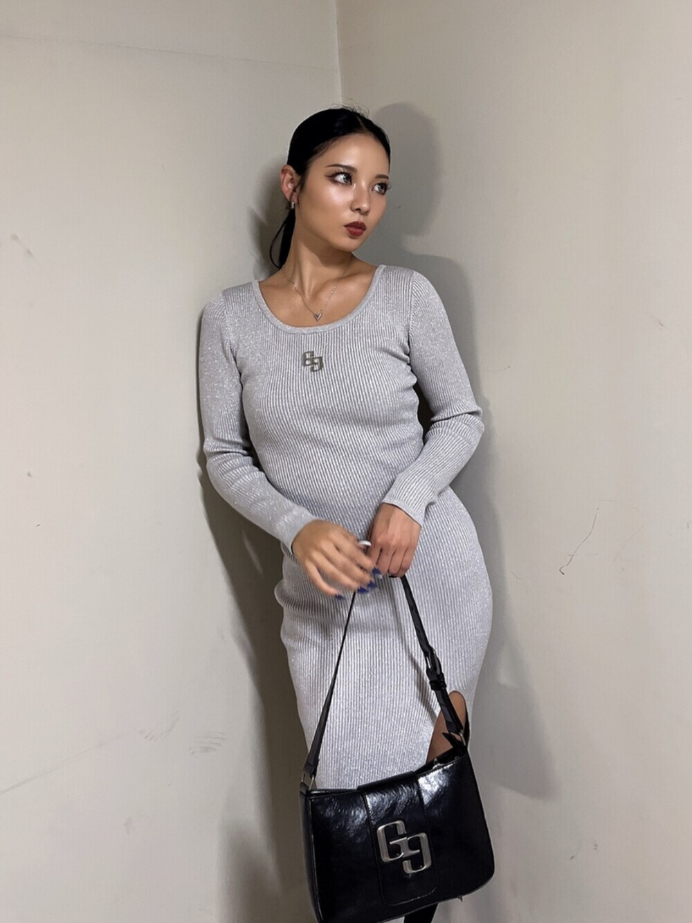 ブラック系のハンドバッグ、ブラック系のブーツ、シルバー系のワンピースを着用したレディースの秋コーディネートの5枚目の写真