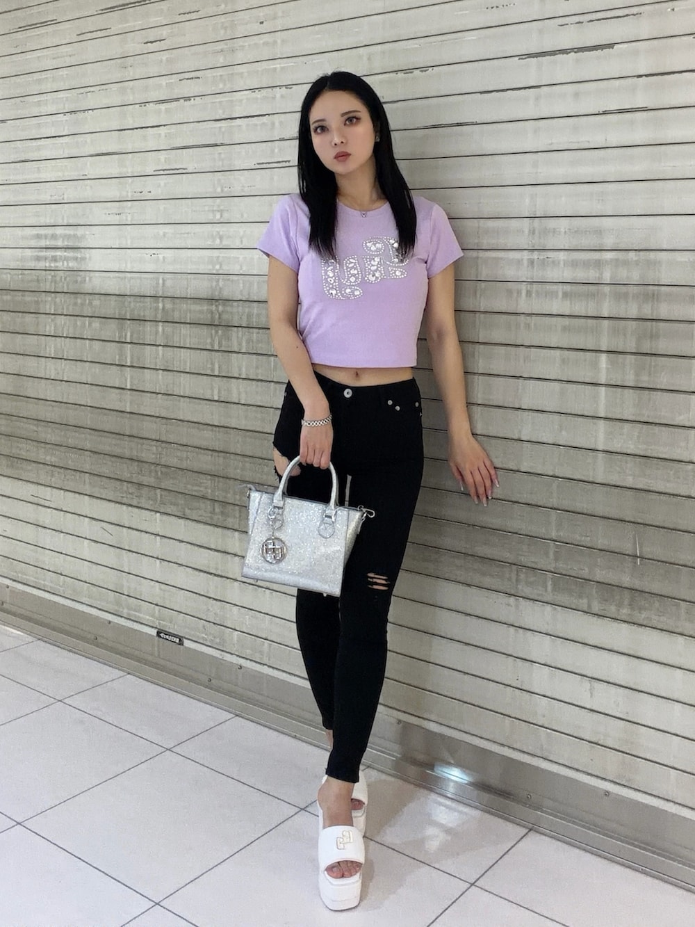 パープル系のTシャツ/カットソー、ブラック系のデニムパンツ、シルバー系のハンドバッグを着用したレディースの春コーディネートの2枚目の写真
