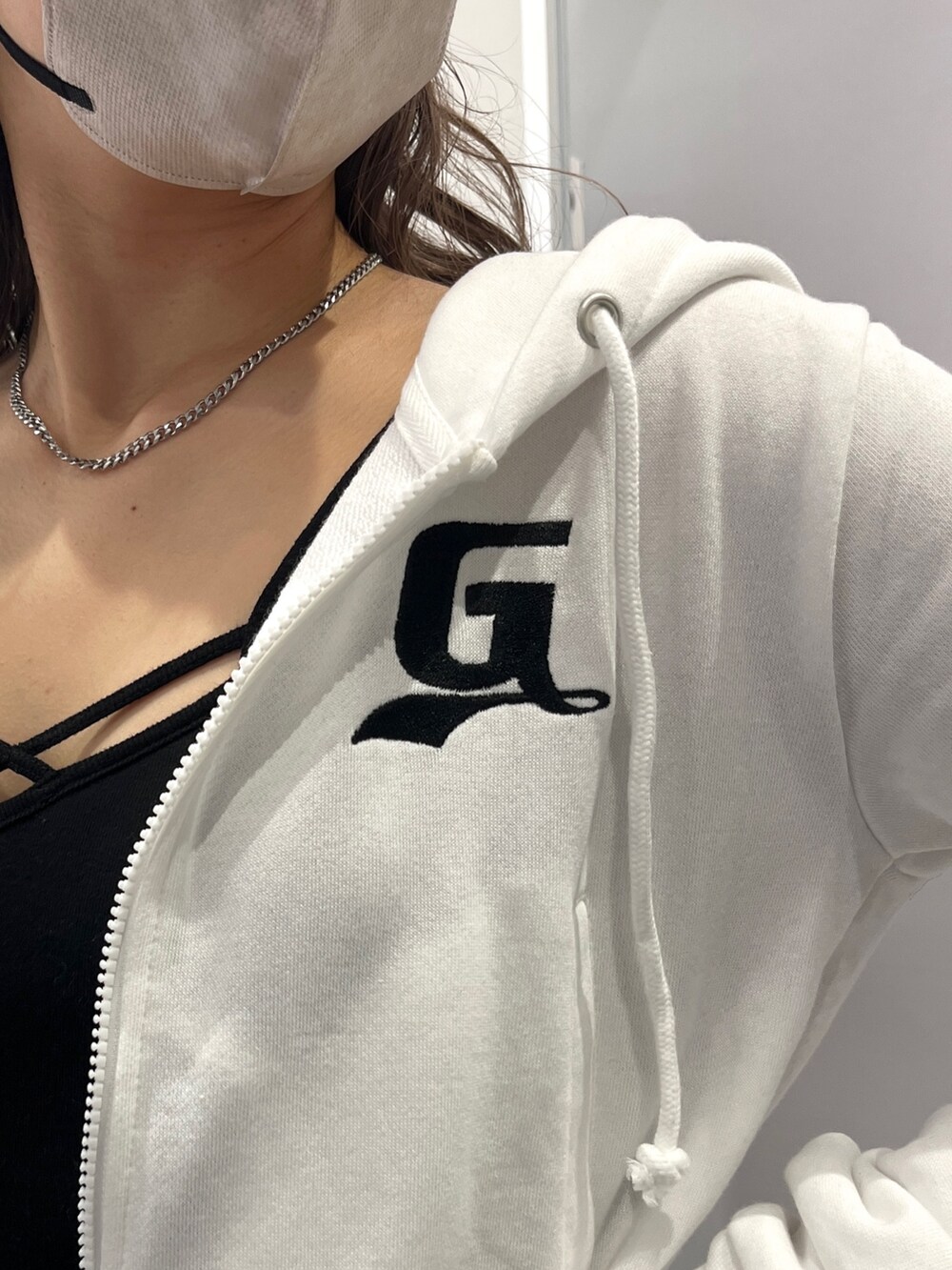 ホワイト系のパーカー、ブラック系のキャミソール、グレー系のスカートを着用したレディースの冬コーディネートの3枚目の写真