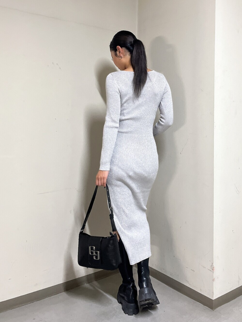 ブラック系のハンドバッグ、ブラック系のブーツ、シルバー系のワンピースを着用したレディースの秋コーディネートの3枚目の写真
