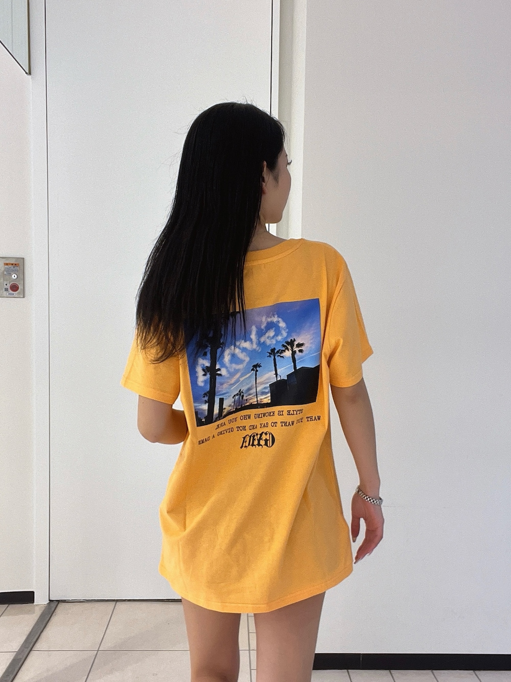 オレンジ系のTシャツ/カットソー、ブルー系のデニムパンツを着用したレディースの春コーディネートの6枚目の写真