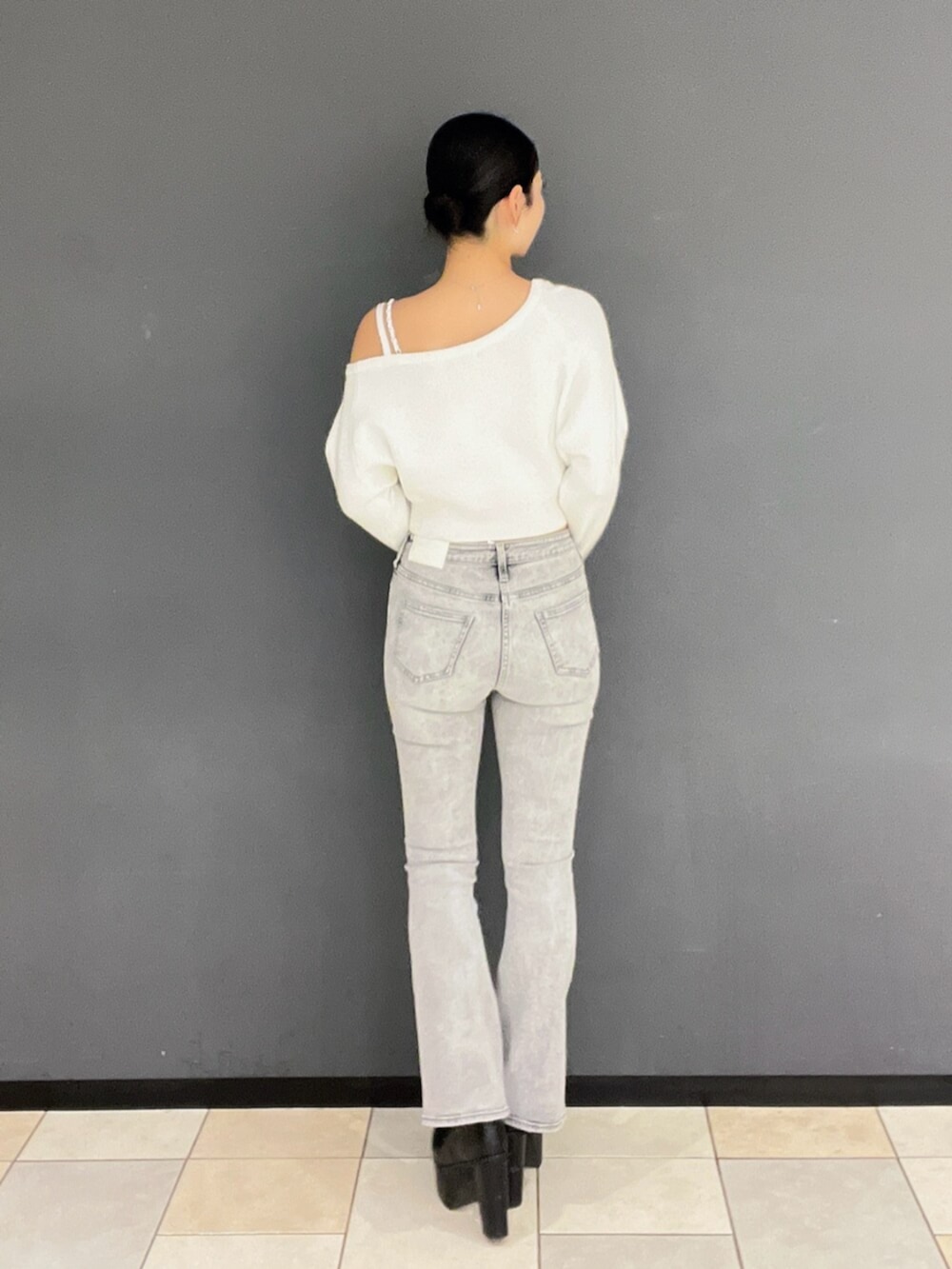 グレー系のデニムパンツ、ブラック系のブーツ、ホワイト系のニット/セーターを着用したレディースの秋コーディネートの4枚目の写真