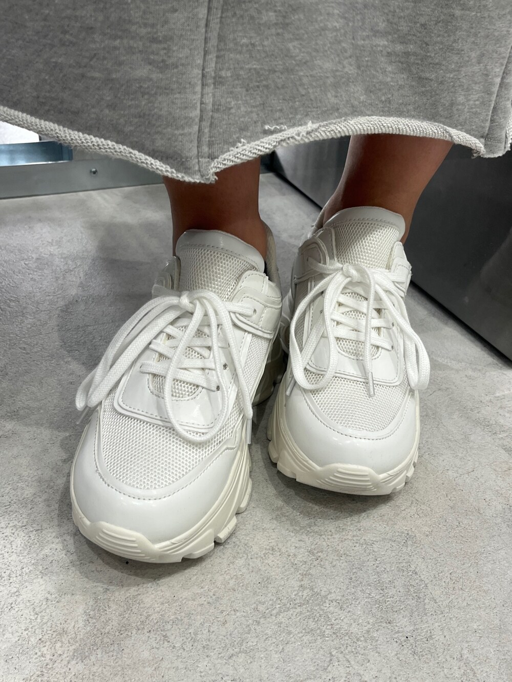 ホワイト系のパーカー、ブラック系のキャミソール、グレー系のスカートを着用したレディースの冬コーディネートの6枚目の写真