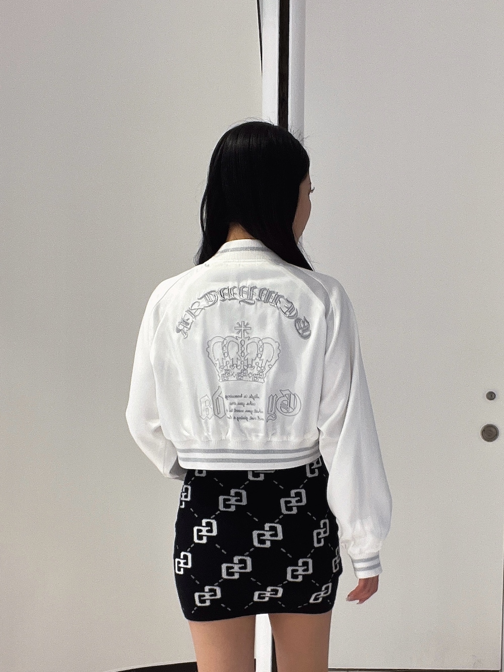 ブラック系のワンピース、ブラック系のブーツ、ホワイト系のブルゾンを着用したレディースの春コーディネートの5枚目の写真