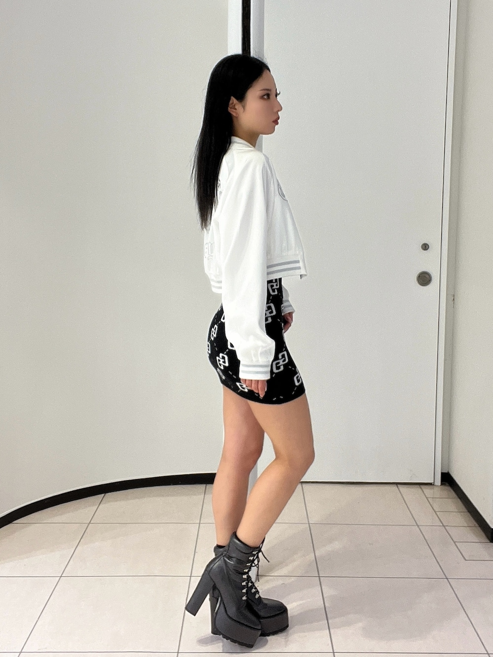 ブラック系のワンピース、ブラック系のブーツ、ホワイト系のブルゾンを着用したレディースの春コーディネートの3枚目の写真