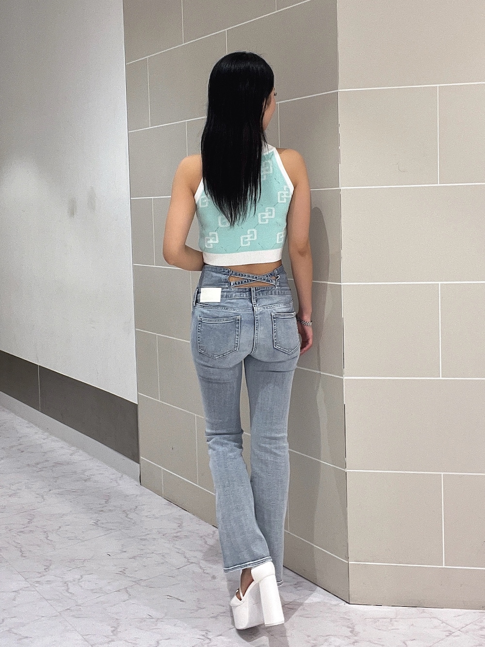 ブルー系のデニムパンツ、ホワイト系のサンダル、グリーン系のニット/セーターを着用したレディースの春コーディネートの4枚目の写真