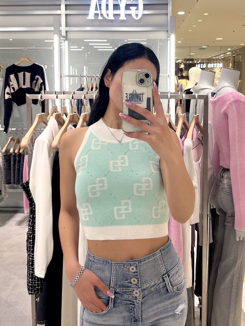 ブルー系のデニムパンツ、ホワイト系のサンダル、グリーン系のニット/セーターを着用したレディースの春コーディネートの5枚目の写真