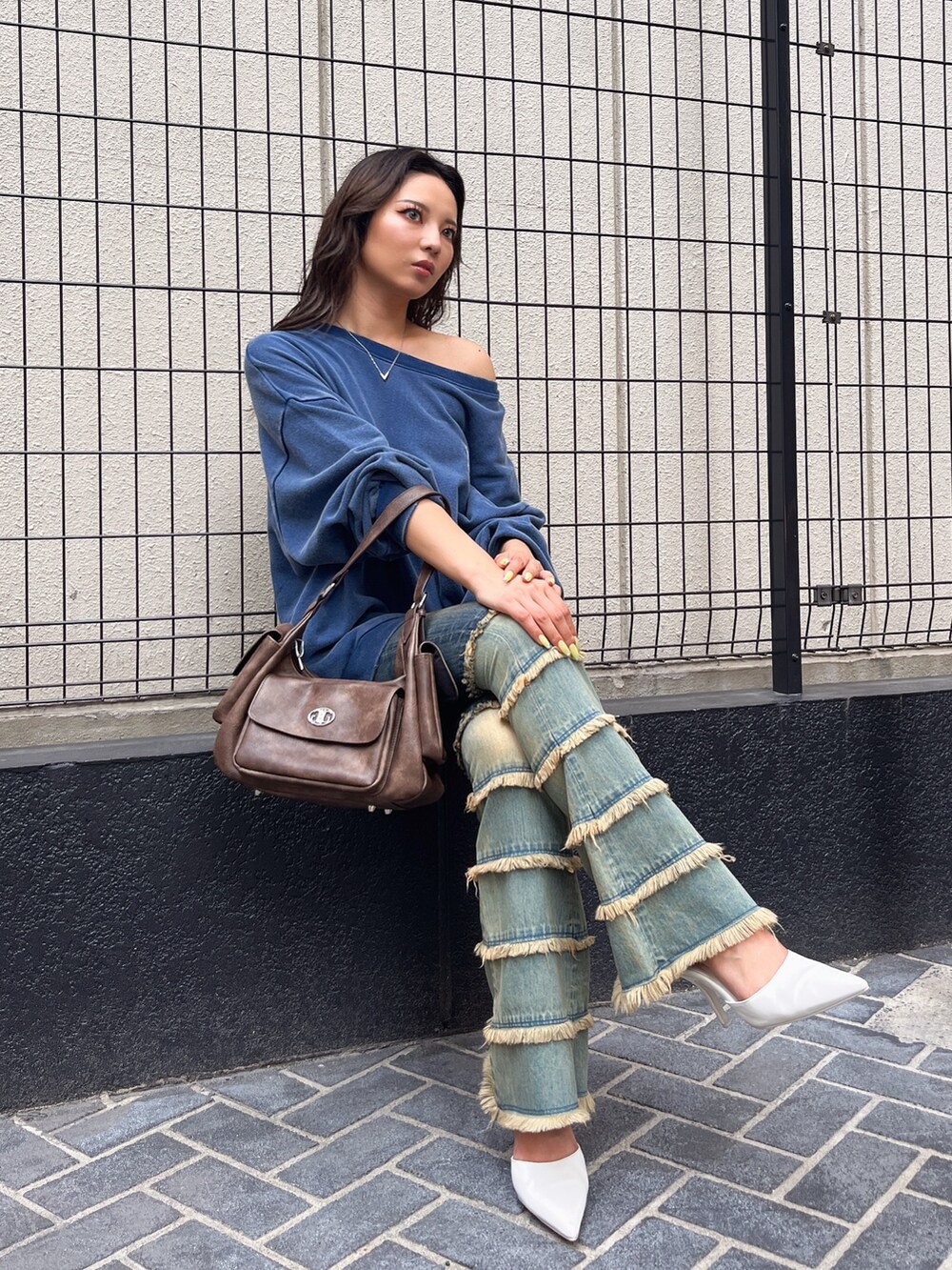 ブルー系のスウェット、ブルー系のデニムパンツ、ブラウン系のハンドバッグを着用したレディースの夏コーディネートの2枚目の写真