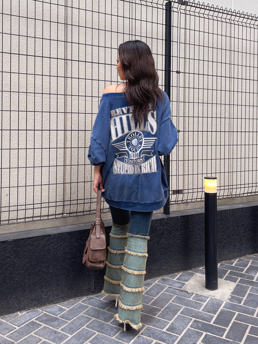 ブルー系のスウェット、ブルー系のデニムパンツ、ブラウン系のハンドバッグを着用したレディースの夏コーディネートの3枚目の写真