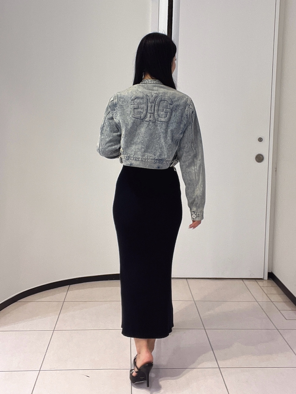 ブラック系のワンピース、ブラック系のパンプス、ブルー系のデニムジャケットを着用したレディースの春コーディネートの4枚目の写真