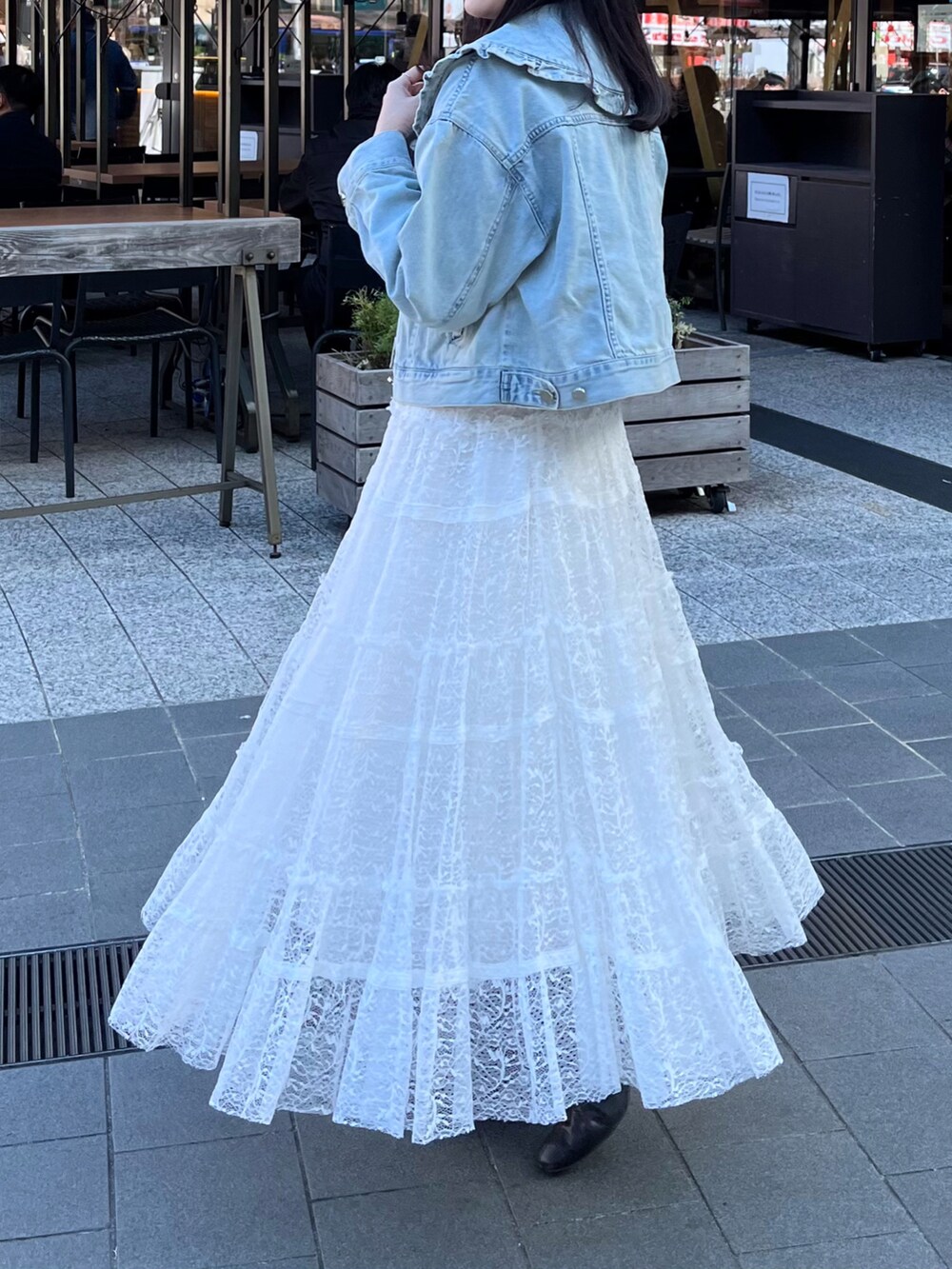 ホワイト系のスカート、ブルー系のデニムジャケット、ベージュ系のタンクトップを着用したレディースの冬コーディネートの3枚目の写真