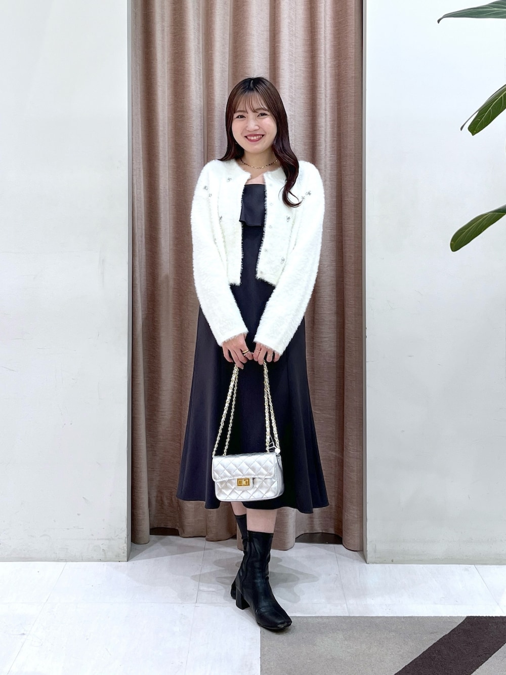 ホワイト系のカーディガン/ボレロ、グレー系のワンピース、シルバー系のハンドバッグを着用したレディースの冬コーディネートの2枚目の写真