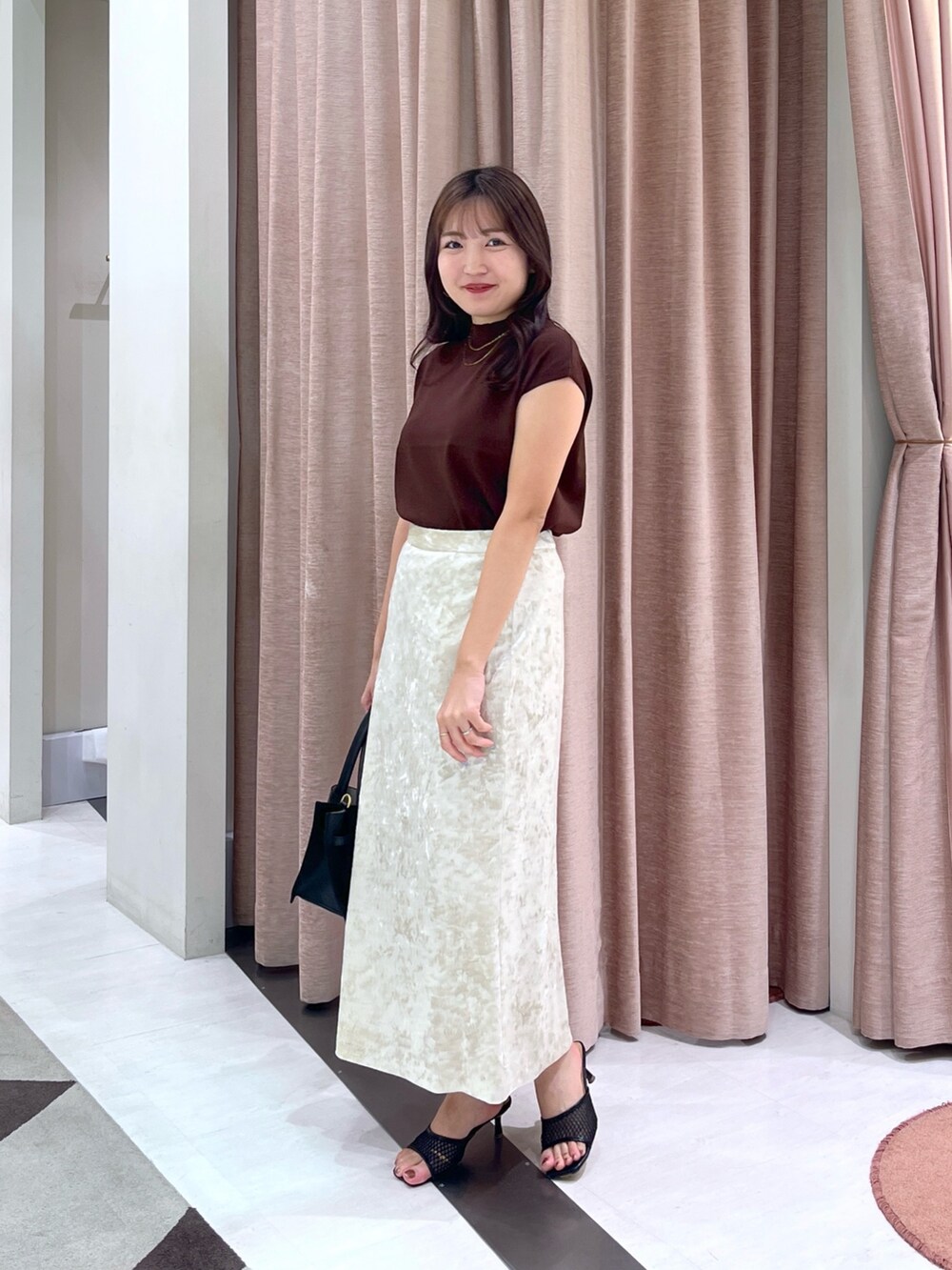 ブラウン系のニット/セーター、ベージュ系のスカート、ブラック系のトートバッグを着用したレディースの夏コーディネートの3枚目の写真