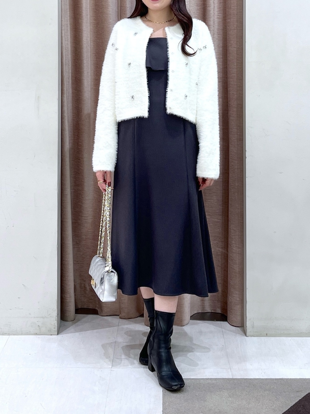 ホワイト系のカーディガン/ボレロ、グレー系のワンピース、シルバー系のハンドバッグを着用したレディースの冬コーディネートの4枚目の写真