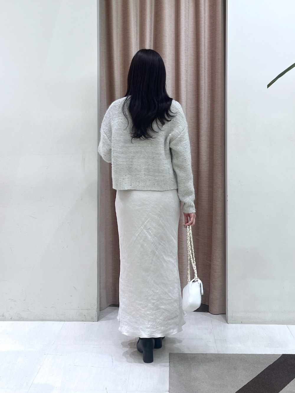 ホワイト系のチューブトップ、ホワイト系のカーディガン/ボレロ、グレー系のスカートを着用したレディースの秋コーディネートの4枚目の写真