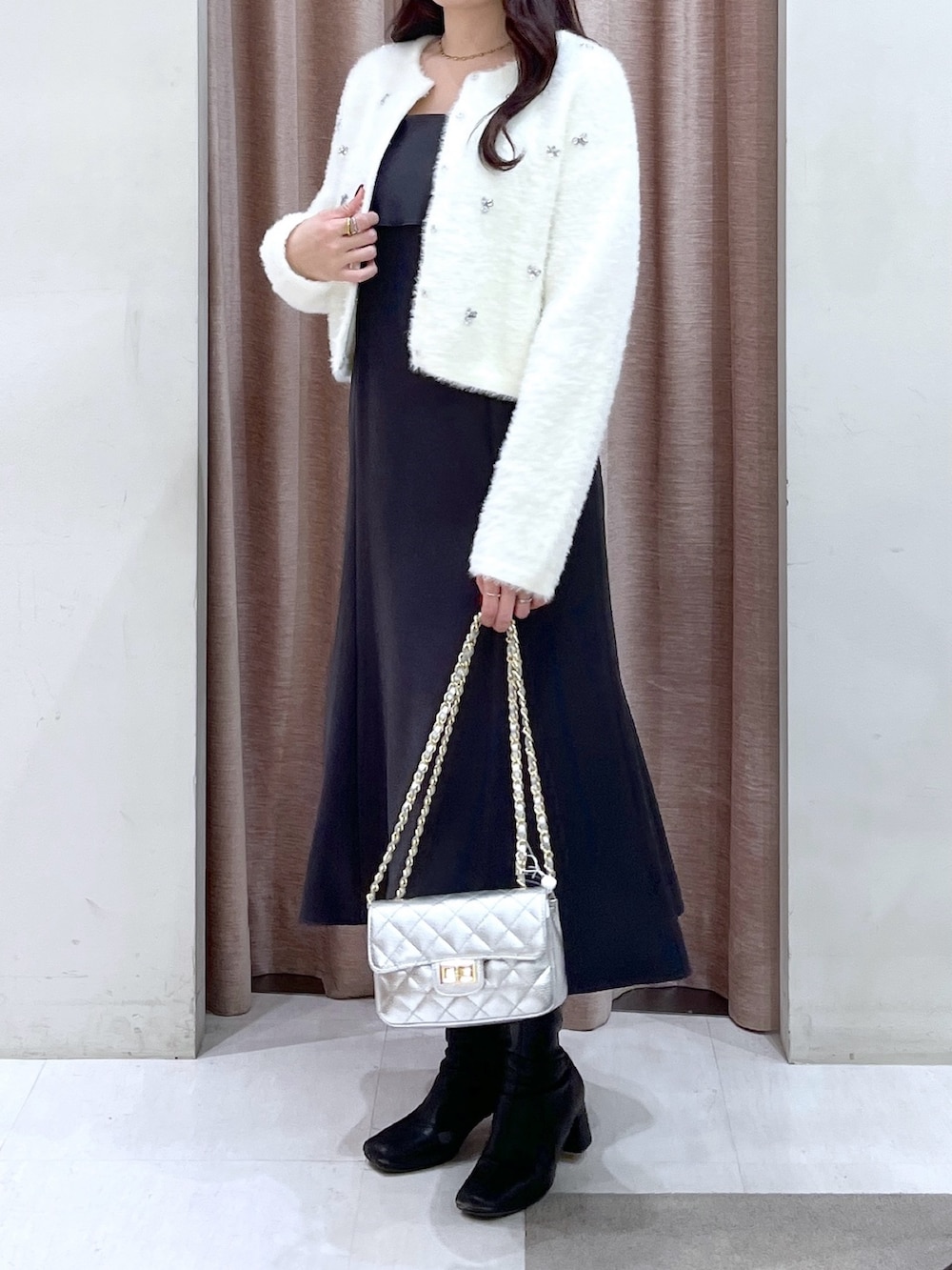 ホワイト系のカーディガン/ボレロ、グレー系のワンピース、シルバー系のハンドバッグを着用したレディースの冬コーディネートの5枚目の写真