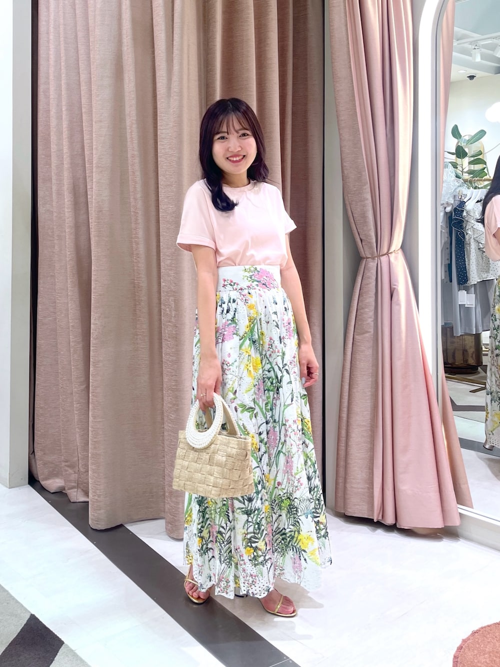 ホワイト系のスカート、ピンク系のTシャツ/カットソー、ベージュ系のトートバッグを着用したレディースの夏コーディネートの2枚目の写真