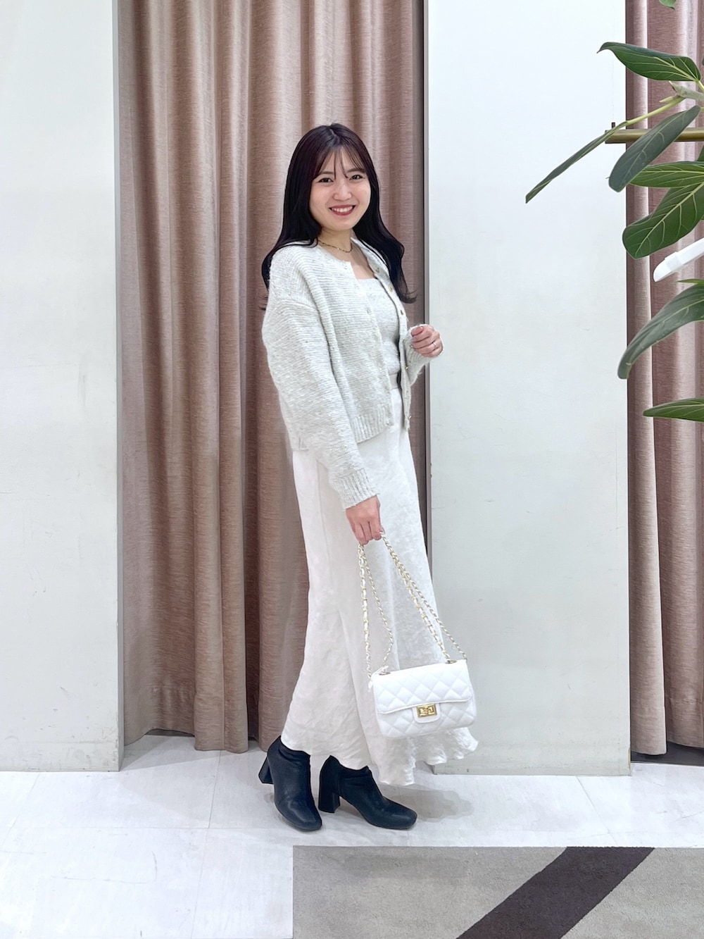 ホワイト系のチューブトップ、ホワイト系のカーディガン/ボレロ、グレー系のスカートを着用したレディースの秋コーディネートの2枚目の写真