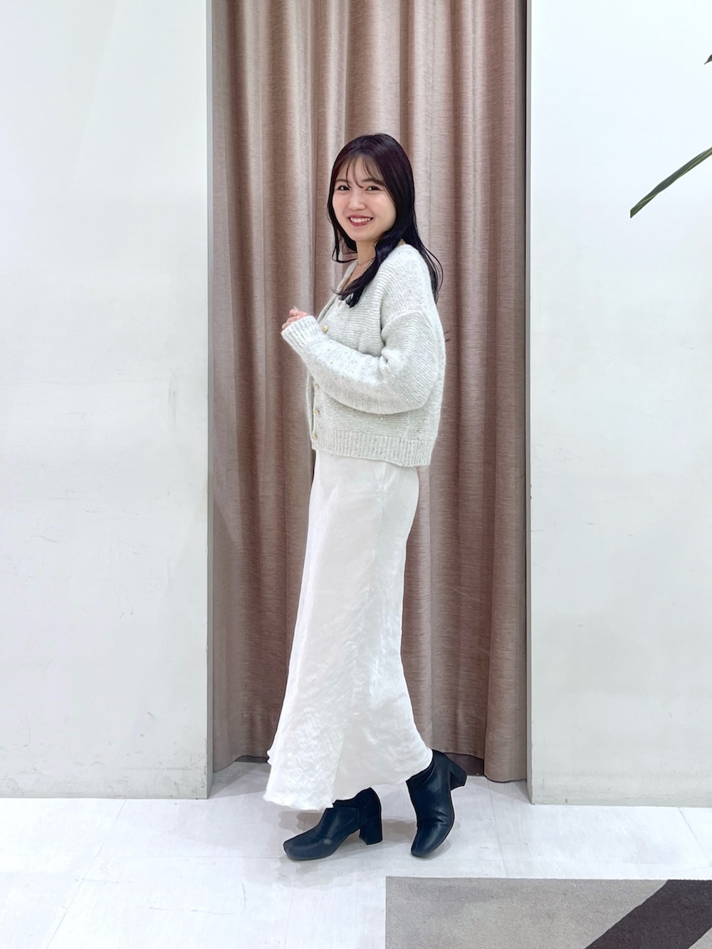 ホワイト系のチューブトップ、ホワイト系のカーディガン/ボレロ、グレー系のスカートを着用したレディースの秋コーディネートの3枚目の写真