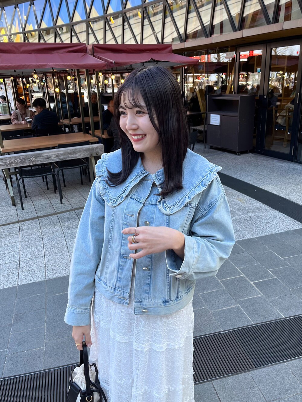 ホワイト系のスカート、ブルー系のデニムジャケット、ベージュ系のタンクトップを着用したレディースの冬コーディネートの4枚目の写真