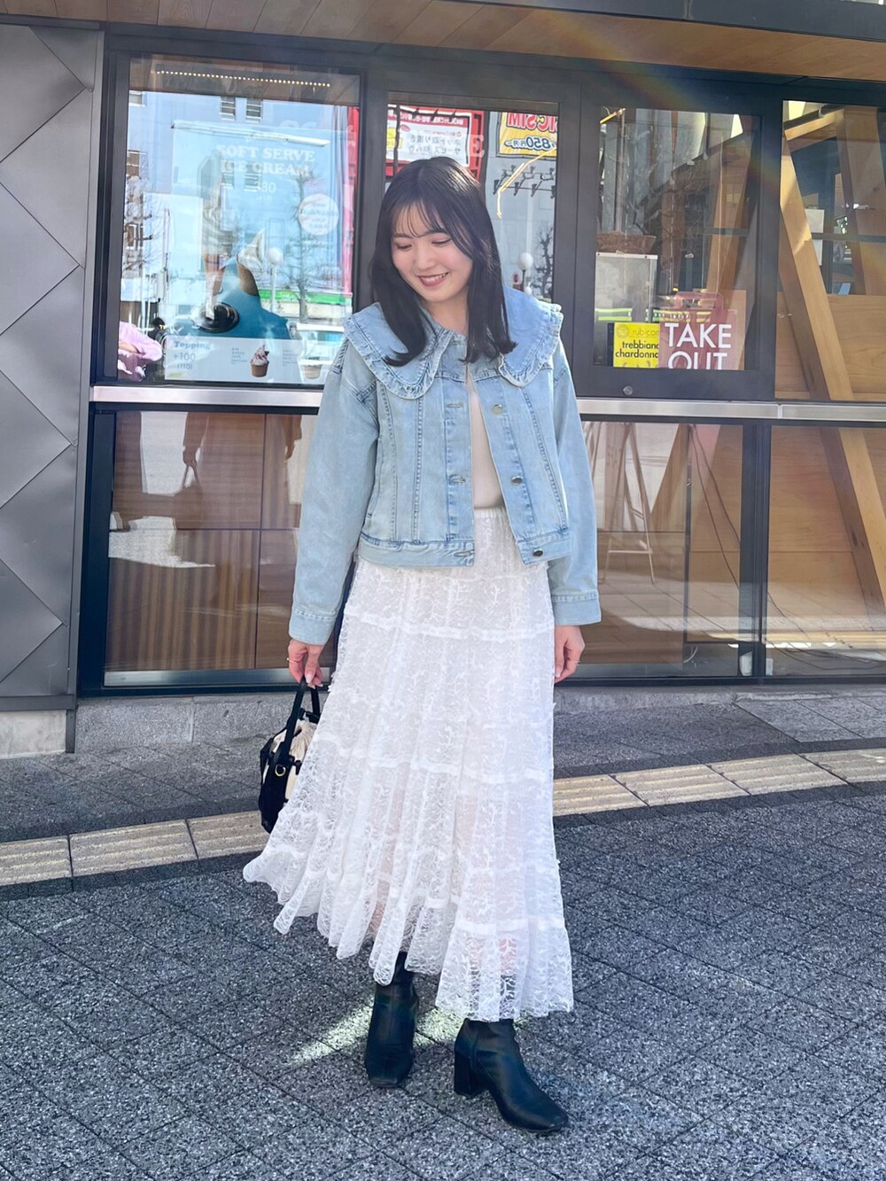 ホワイト系のスカート、ブルー系のデニムジャケット、ベージュ系のタンクトップを着用したレディースの冬コーディネートの5枚目の写真