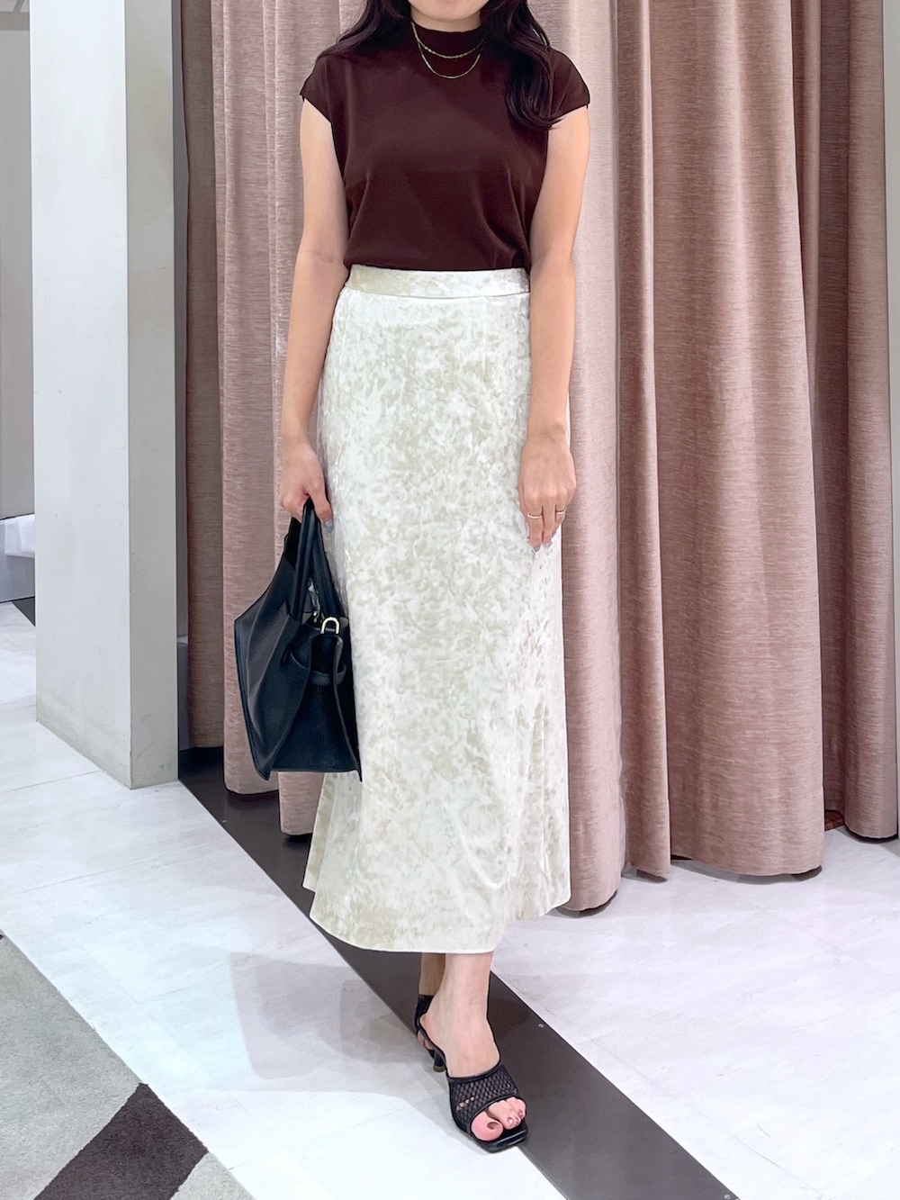 ブラウン系のニット/セーター、ベージュ系のスカート、ブラック系のトートバッグを着用したレディースの夏コーディネートの4枚目の写真