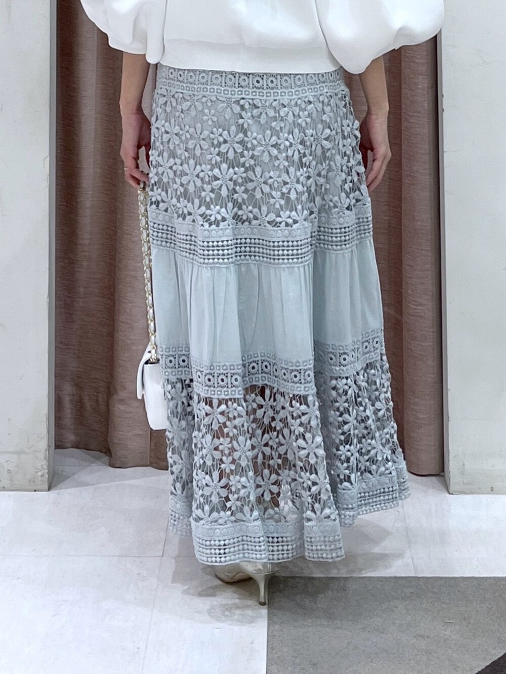 ホワイト系のカーディガン/ボレロ、ブルー系のスカートを着用したレディースの冬コーディネートの5枚目の写真