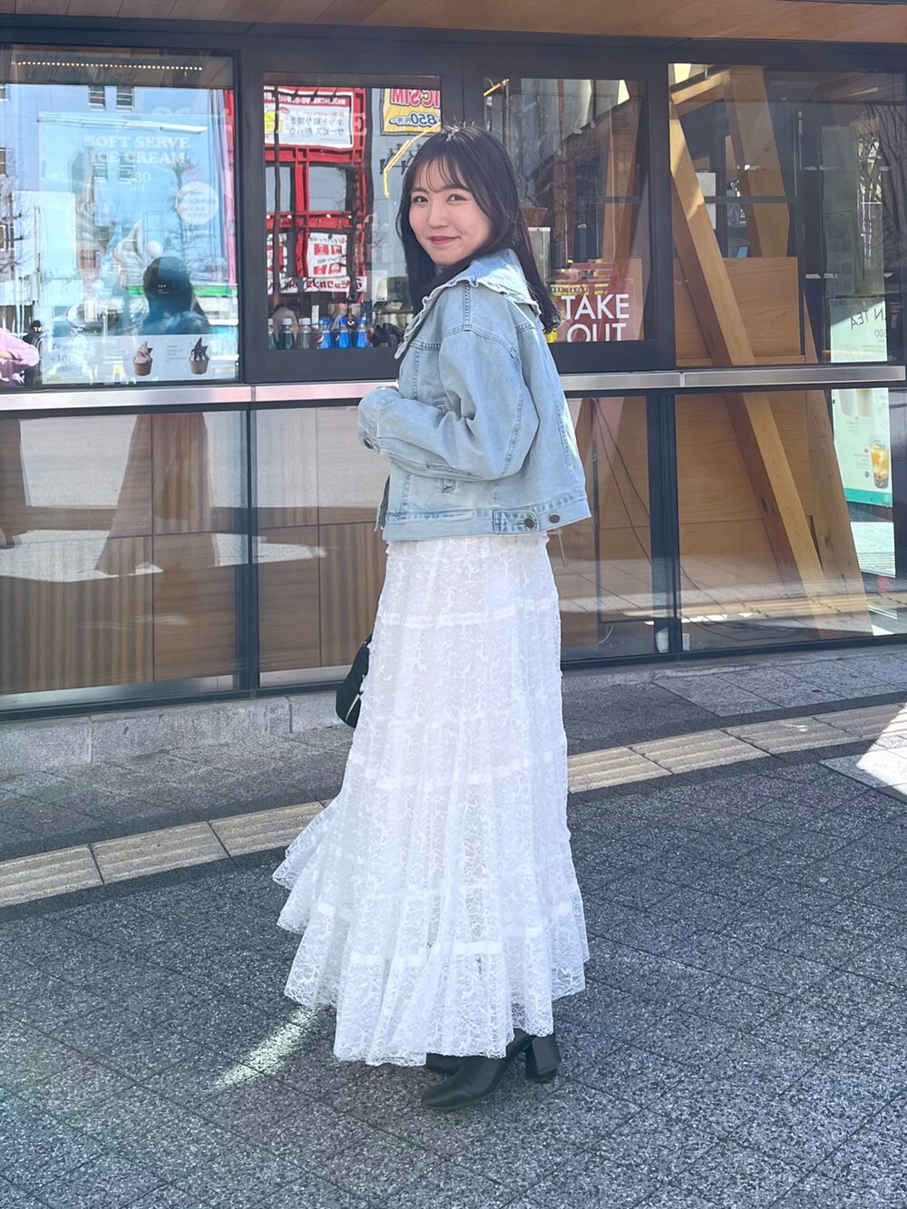 ホワイト系のスカート、ブルー系のデニムジャケット、ベージュ系のタンクトップを着用したレディースの冬コーディネートの2枚目の写真