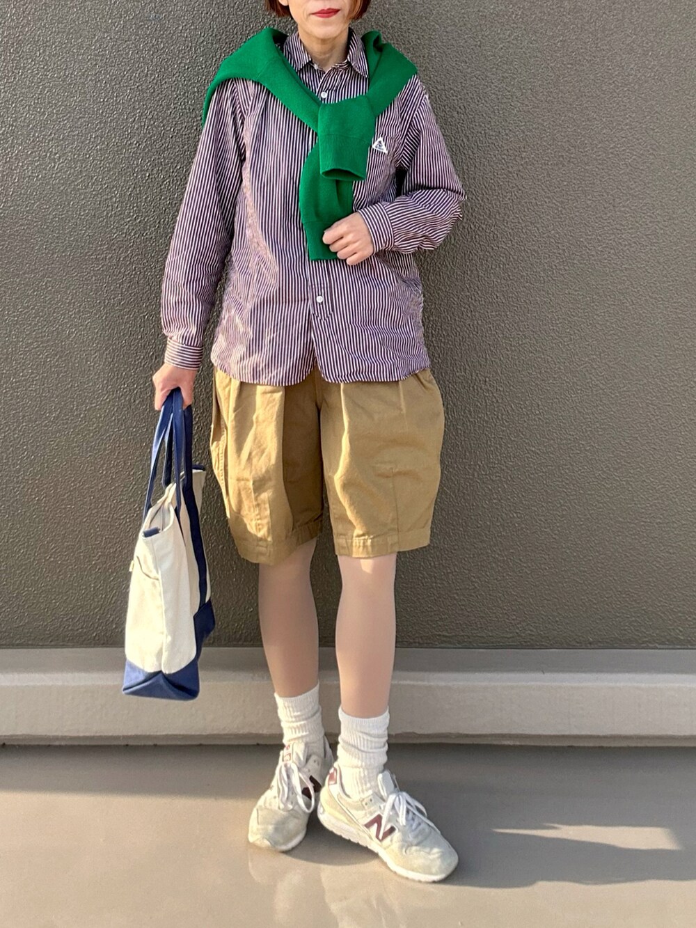 グリーン系のチノパンツ、ブラウン系のシャツ/ブラウス、ホワイト系のスニーカーを着用したレディースの春コーディネートの2枚目の写真